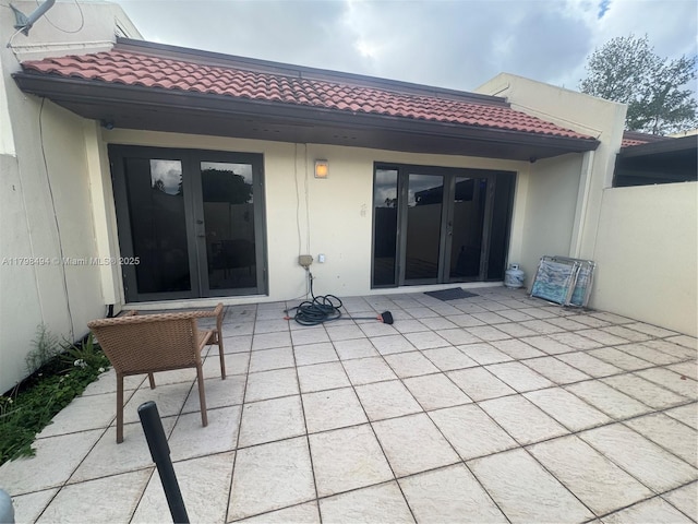 back of house featuring french doors, a patio area, a tiled roof, and stucco siding