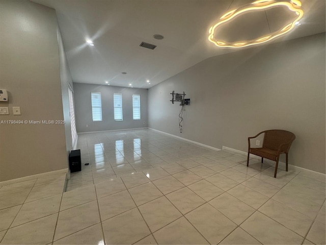 spare room featuring light tile patterned flooring, vaulted ceiling, and baseboards