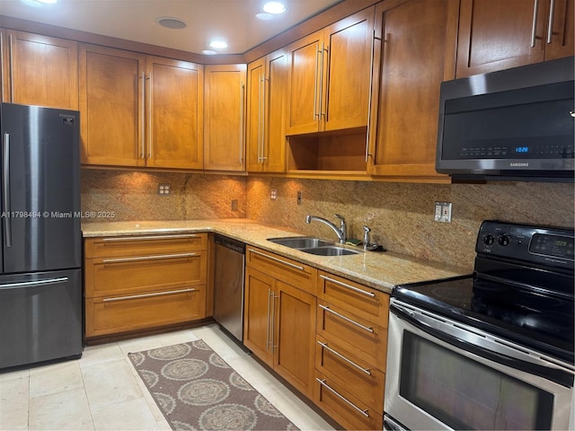 kitchen featuring stainless steel appliances, a sink, light stone counters, decorative backsplash, and recessed lighting