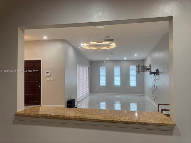 kitchen with a chandelier, baseboards, recessed lighting, light stone counters, and decorative light fixtures