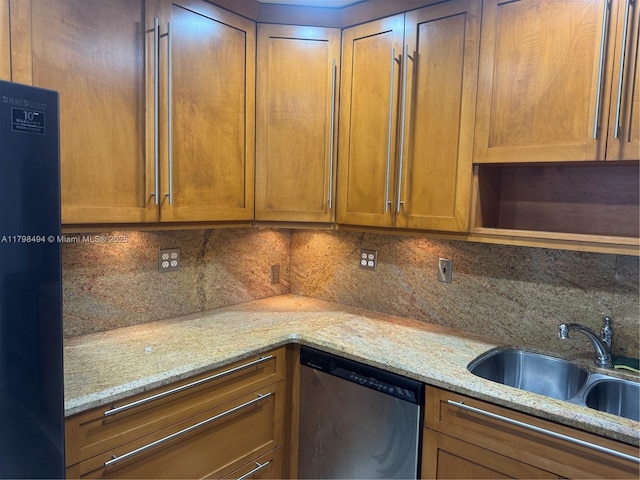 kitchen with stainless steel dishwasher, a sink, refrigerator, tasteful backsplash, and light stone countertops