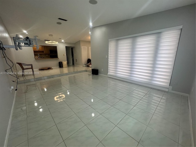 spare room featuring light tile patterned floors and baseboards