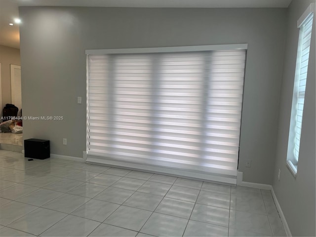 empty room featuring baseboards, light tile patterned flooring, and recessed lighting