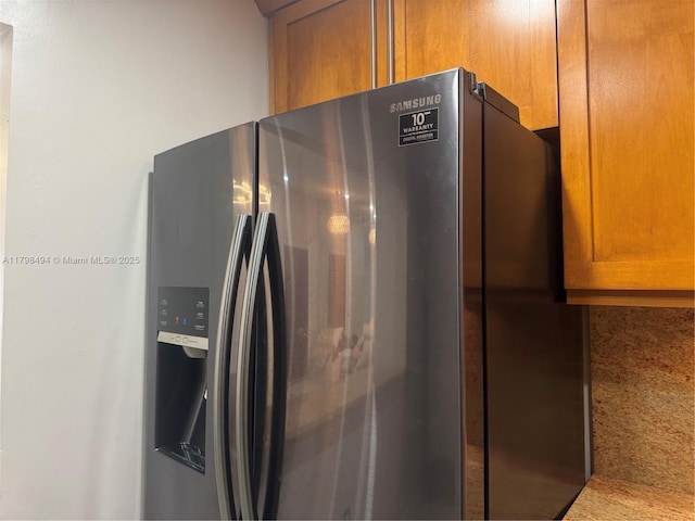 kitchen view of stainless steel fridge and brown cabinetry