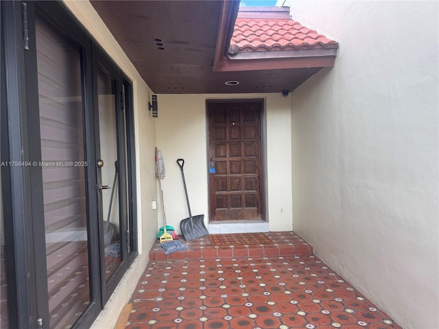 doorway to property featuring stucco siding and a tile roof