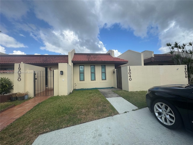 view of front of property featuring a tiled roof, stucco siding, and a gate