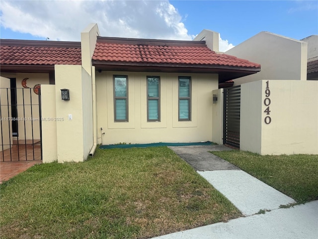view of front of house with stucco siding, a tiled roof, and a gate