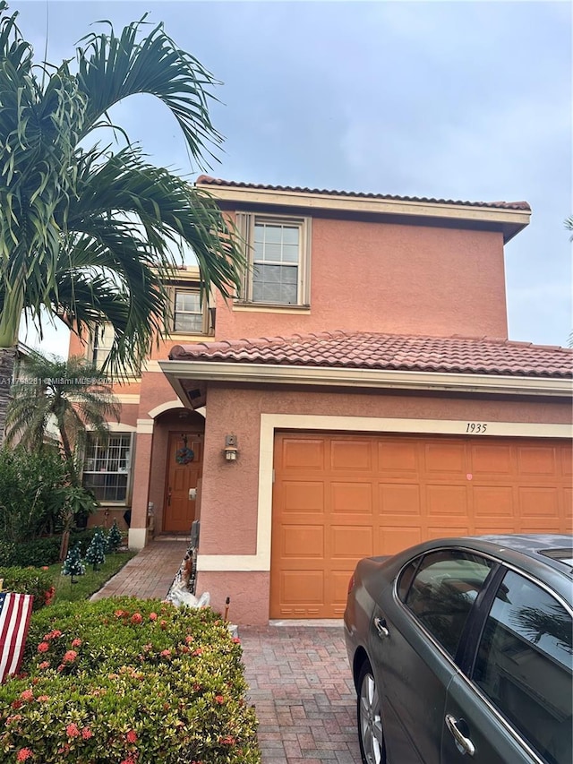 view of front facade featuring stucco siding, a garage, a tile roof, and decorative driveway