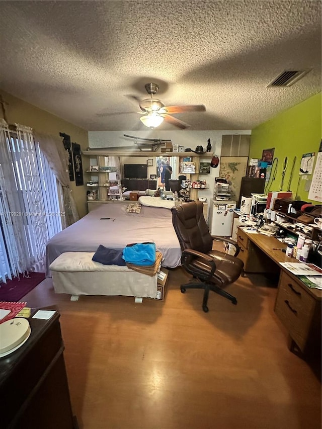 bedroom featuring a textured ceiling, wood finished floors, a ceiling fan, and a desk