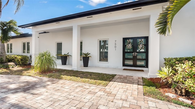 rear view of house with french doors and stucco siding