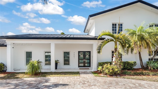 back of property featuring french doors, a standing seam roof, stucco siding, and metal roof