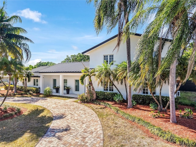 mediterranean / spanish house with stucco siding, a standing seam roof, curved driveway, and metal roof