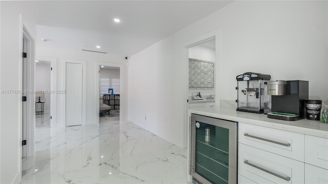 indoor dry bar featuring beverage cooler, light marble finish flooring, and recessed lighting