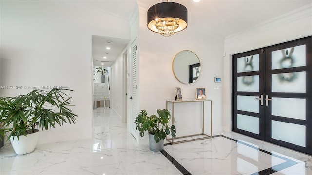 entrance foyer with marble tiled flooring, crown molding, french doors, a chandelier, and baseboards