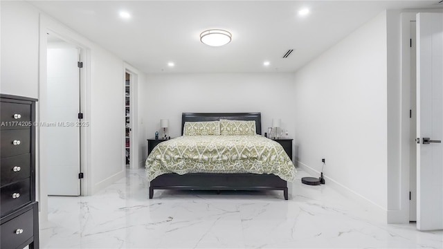 bedroom featuring recessed lighting, marble tiled floors, baseboards, and a walk in closet