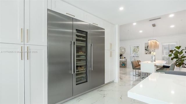 kitchen with stainless steel built in refrigerator, light marble finish floors, crown molding, recessed lighting, and white cabinets