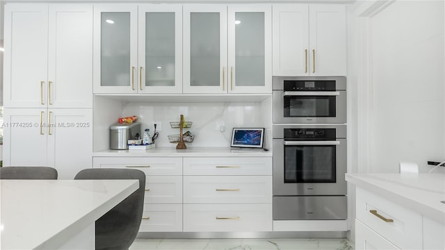 kitchen featuring white cabinetry, double oven, light stone countertops, and glass insert cabinets