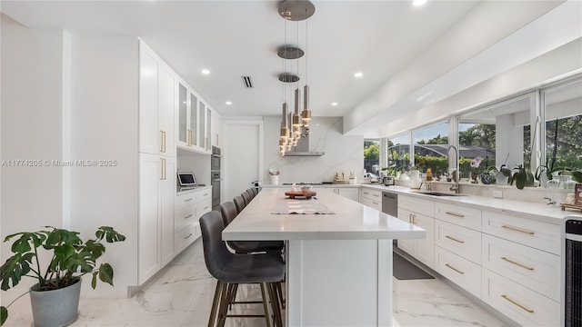 kitchen with a sink, light marble finish floors, recessed lighting, a center island, and a kitchen bar