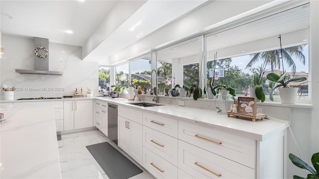 kitchen featuring a sink, wall chimney exhaust hood, light marble finish flooring, and light stone counters