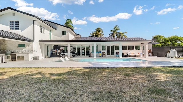 rear view of house featuring a standing seam roof, stucco siding, an outdoor pool, a patio, and metal roof