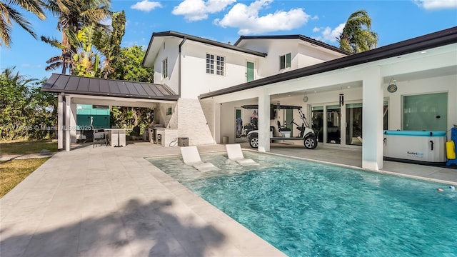 rear view of house with a patio, an outdoor pool, stucco siding, a standing seam roof, and metal roof