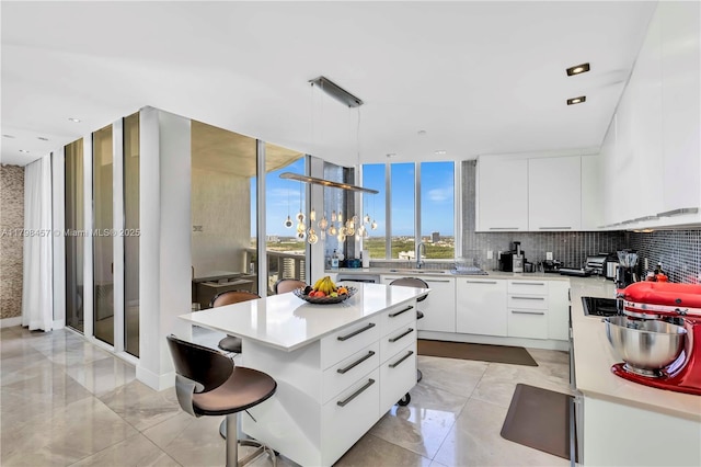 15811 Collins Ave Unit 2506, Sunny Isles Beach, FL 33160 - kitchen with light countertops, modern cabinets, white cabinets, decorative backsplash, and hanging light fixtures
