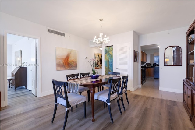 dining space with a chandelier, light wood-style flooring, and baseboards