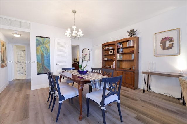 dining area featuring light wood finished floors, a chandelier, and baseboards