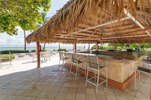 view of patio featuring view of water and beach, fence, and a gazebo