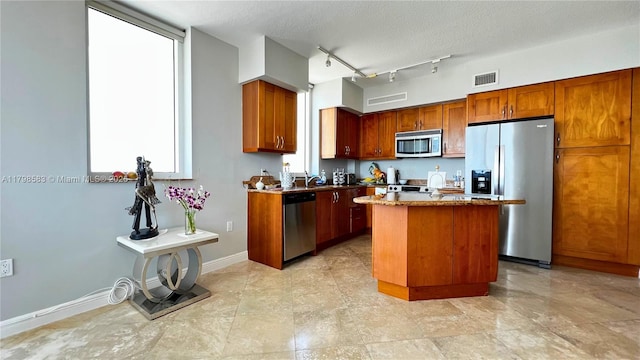 1745 E Hallandale Beach Blvd Unit 2007W, Hallandale Beach, FL 33009 - kitchen featuring appliances with stainless steel finishes, a kitchen island, brown cabinetry, baseboards, and a sink