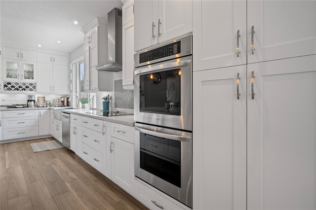 1199 NW 166th Ave, Pembroke Pines, FL 33028 - kitchen with wall chimney range hood, stainless steel appliances, tasteful backsplash, white cabinetry, and light countertops