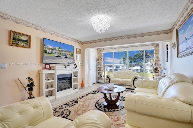 1450 NW 18th Ave Unit 203, Delray Beach, FL 33445 - living area with a textured ceiling, wood finished floors, a glass covered fireplace, and a chandelier