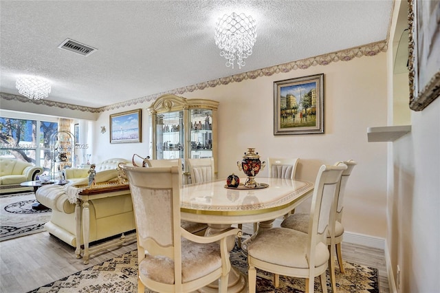 1450 NW 18th Ave Unit 203, Delray Beach, FL 33445 - dining space with a textured ceiling, light wood-style floors, a chandelier, and baseboards