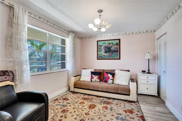 1450 NW 18th Ave Unit 203, Delray Beach, FL 33445 - living area featuring a chandelier, a textured ceiling, baseboards, and wood finished floors