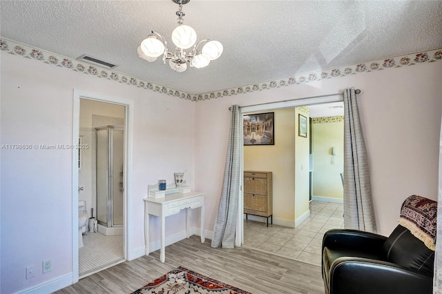 1450 NW 18th Ave Unit 203, Delray Beach, FL 33445 - living area with a chandelier, a textured ceiling, light wood-type flooring, and baseboards