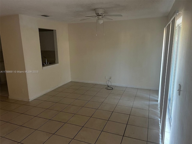 empty room with a ceiling fan, light tile patterned floors, and baseboards