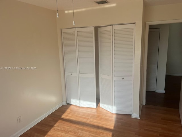 unfurnished bedroom featuring a closet, baseboards, and wood finished floors
