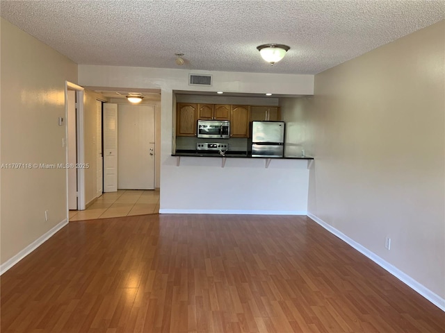 8180 Geneva Ct Unit 224, Doral, FL 33166 - kitchen featuring appliances with stainless steel finishes, wood finished floors, a textured ceiling, dark countertops, and baseboards