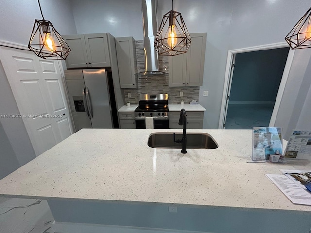 kitchen featuring appliances with stainless steel finishes, a sink, gray cabinets, light stone countertops, and decorative backsplash