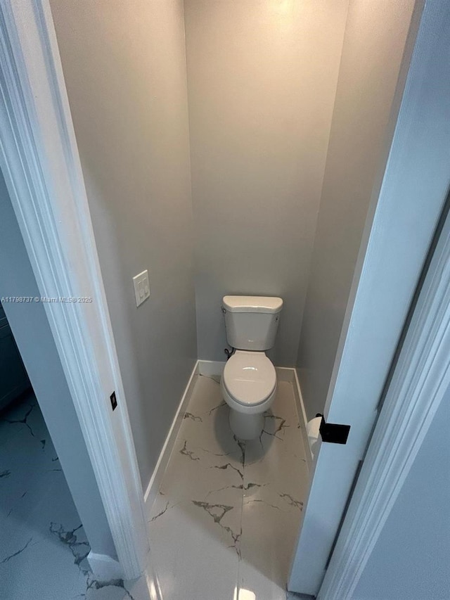 bathroom featuring marble finish floors, baseboards, and toilet