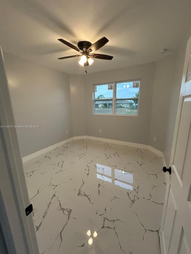 spare room featuring ceiling fan, baseboards, marble finish flooring, and a textured ceiling
