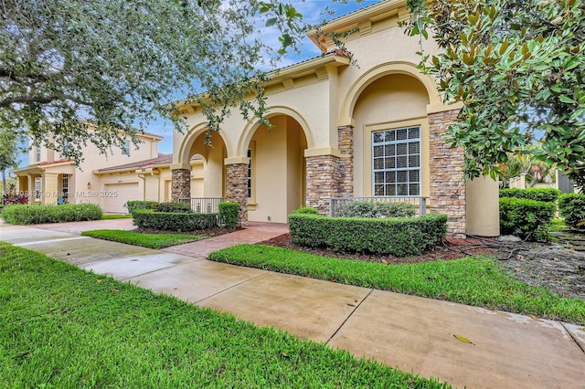 mediterranean / spanish-style house with stucco siding, stone siding, an attached garage, and driveway