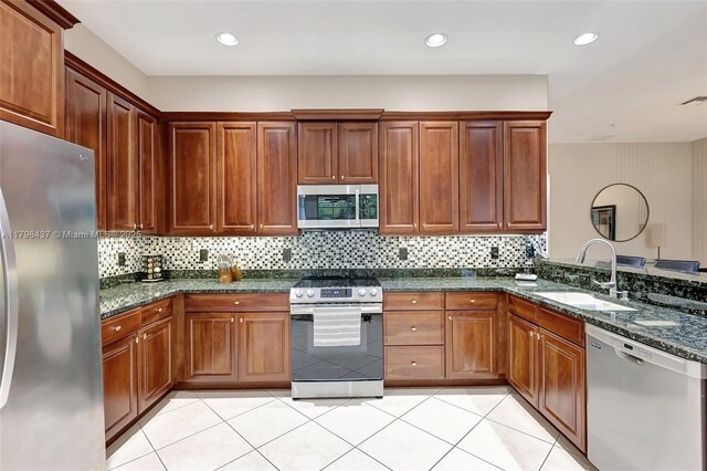kitchen featuring stainless steel appliances, a sink, tasteful backsplash, dark stone counters, and recessed lighting