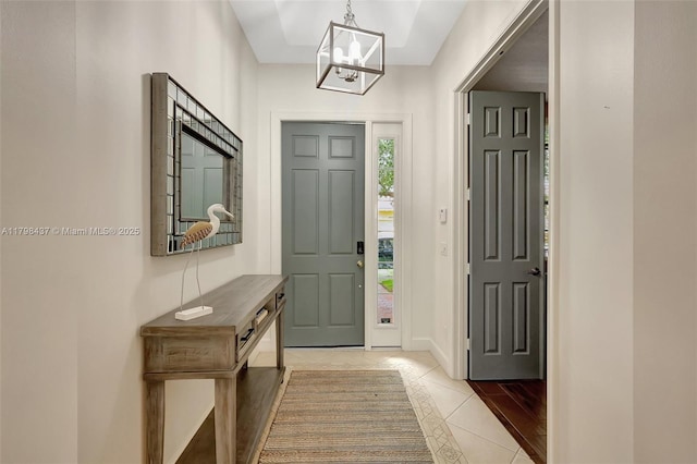foyer entrance with a chandelier, light tile patterned flooring, and baseboards