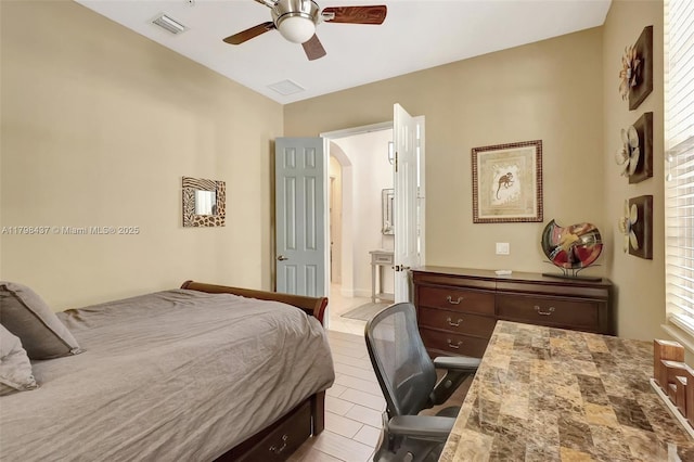 tiled bedroom with connected bathroom, arched walkways, and a ceiling fan