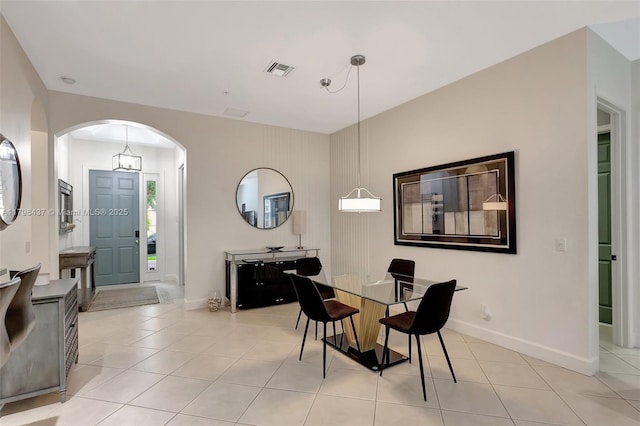 dining room featuring arched walkways, baseboards, and light tile patterned floors