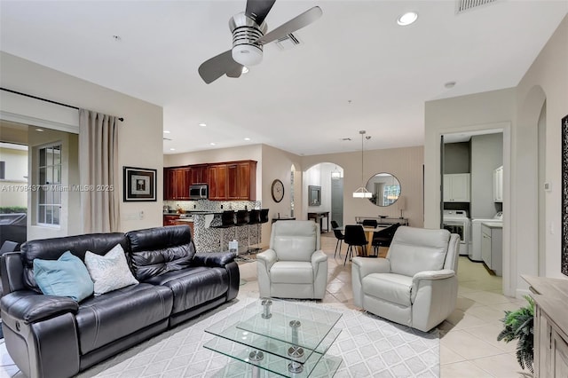 living room with arched walkways, a ceiling fan, light tile patterned floors, washer / clothes dryer, and recessed lighting