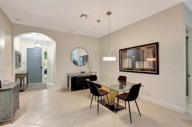 dining space featuring arched walkways, light tile patterned floors, and baseboards