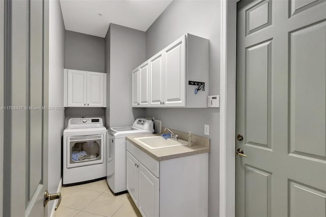 clothes washing area with cabinet space, washing machine and clothes dryer, and light tile patterned floors