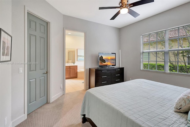 bedroom with light colored carpet, baseboards, ensuite bath, and a ceiling fan